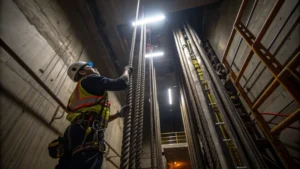 A technician lubricating elevator steel wire ropes in an industrial shaft